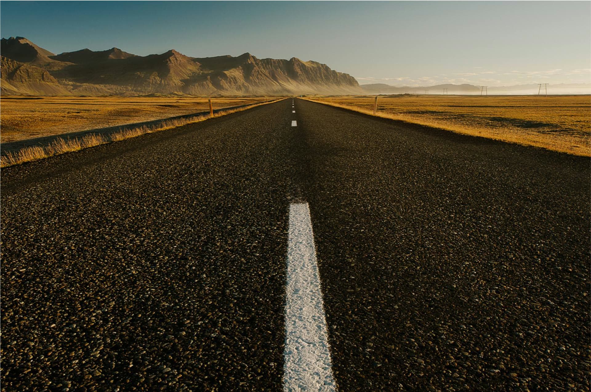 An open road running toward distant mountains at first light