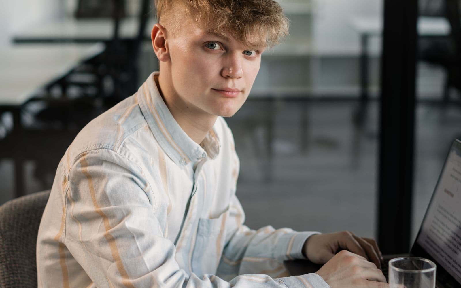 A young professional working at a laptop in a bright, plant-filled office